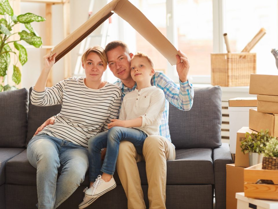 Family holding cardboard roof above their heads